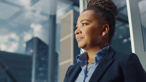 portrait of successful black businesswoman riding glass elevator to office in modern business center. african american female looking at modern skyscrapers out of the panorama window in the lift.