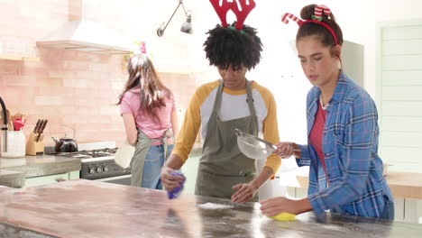 christmas time, baking holiday treats together, women friends wearing festive headbands in kitchen