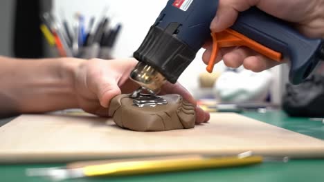 creating detailed sculptures: using a heat gun for precision on clay models in a crafting workspace