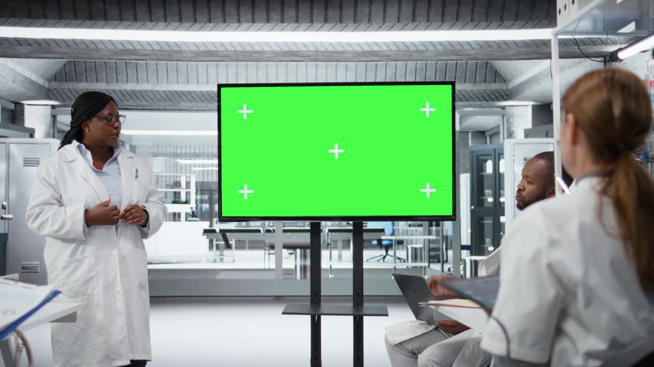 Display a schermo verde utilizzato da un esperto di biotecnologie in laboratorio mentre presenta ai colleghi.