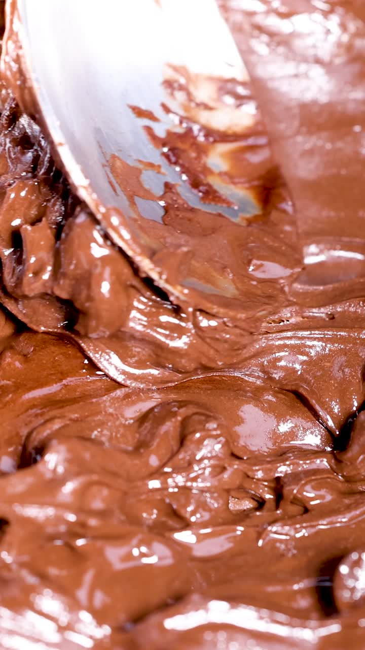 Un cucchiaio mescola gocce di cioccolato che si sciolgono in padella