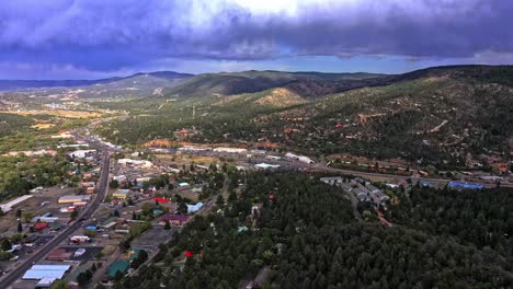 Village-surrounded-by-hills-and-forested-mountains-under-a-cloudy-sky