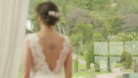 medium shot of a bride walking with a bouquet of flowers, wearing a lace dress as she heads to the ceremony.