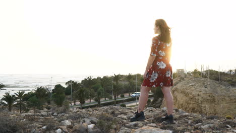 woman in red dress overlooking a scenic landscape at sunset