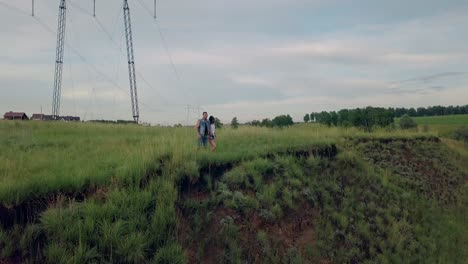 aerial-view-young-couple-walks-to-green-meadow-edge