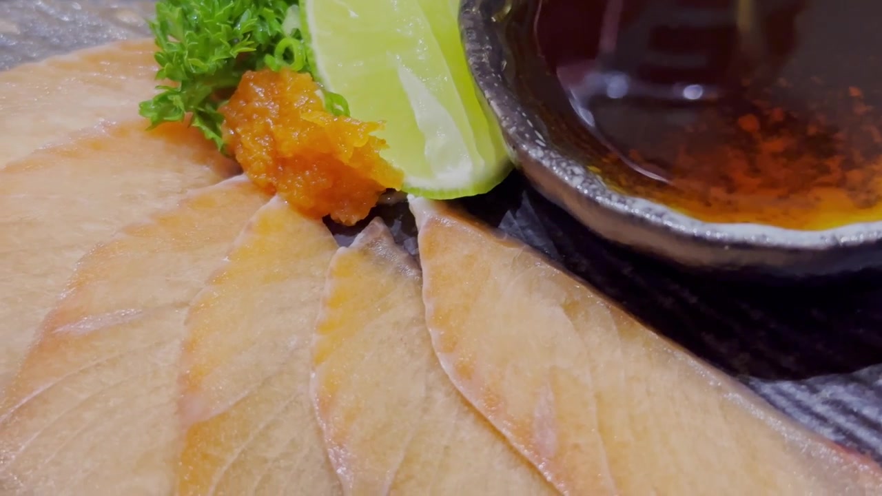Video cận cảnh các loại sashimi tươi ngon được sắp xếp đẹp mắt trên đĩa phục vụ trong một nhà hàng Nhật Bản. Cách trình bày hải sản sống cao cấp thể hiện truyền thống ẩm thực Nhật Bản đích thực và sự thanh lịch.