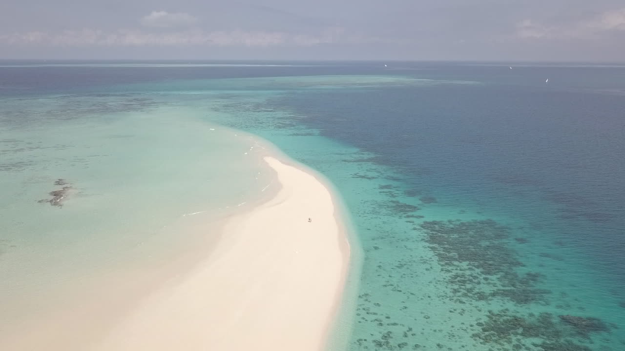 따뜻한 열대 바다의 모래섬에 있는 관광 커플: 공중 휴양지
