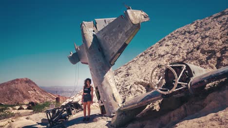 4K-UHD-Cinemagraph-of-a-young-brunette-woman-standing-next-to-a-wreck-of-an-old-American-military-air-plane