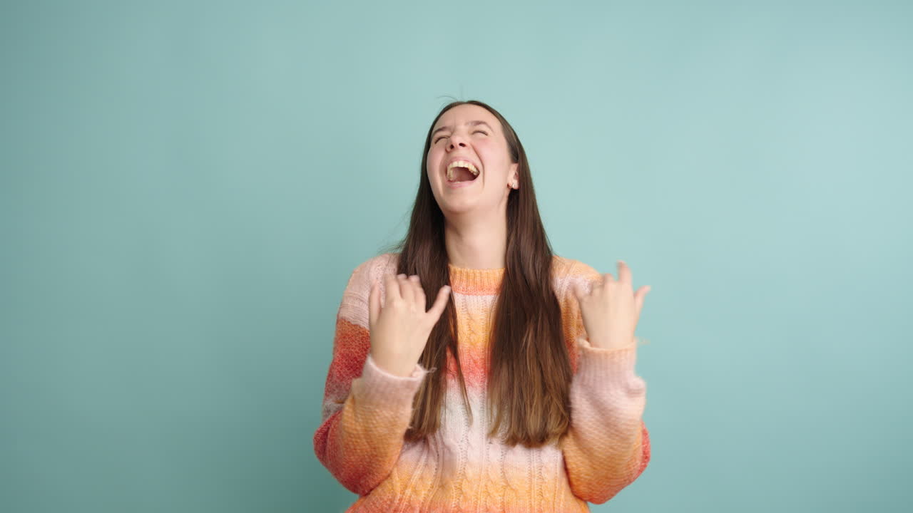 Young woman laughing joyfully against a turquoise background