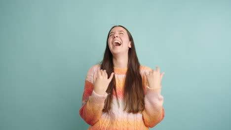 young woman laughing joyfully against a turquoise background