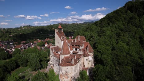 scenic pull-back aerial shot revealing the bran castle. iconic historic architecture among the green hills and forests of transylvania.