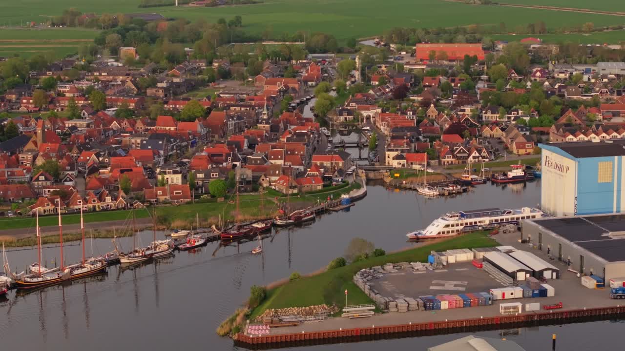 Drohnenansicht des Dorfes Makkum mit Kanal, Booten, Brücke und Dächern