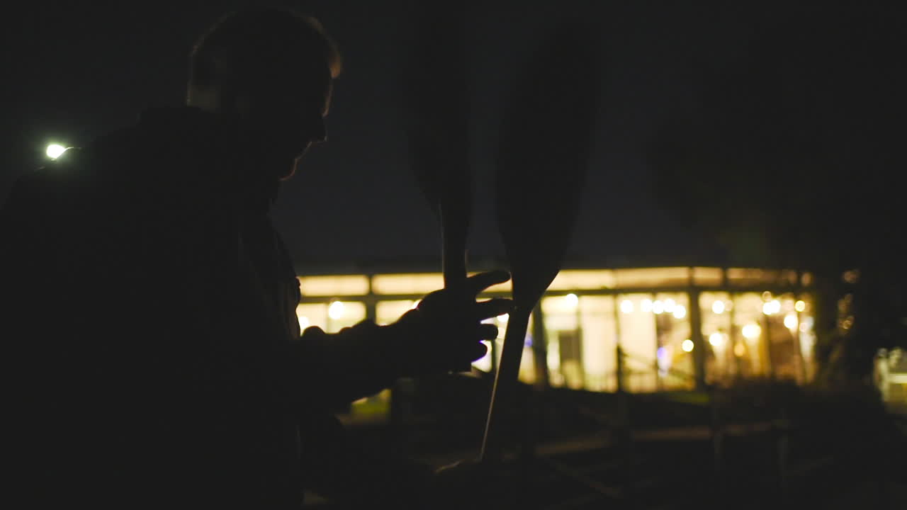 Man Assembling A Kayak Paddle In London, UK At Night - medium shot