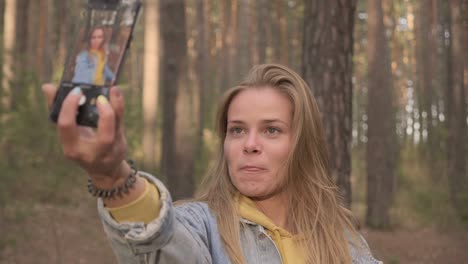 young girl making selfie at phone in sunny forest