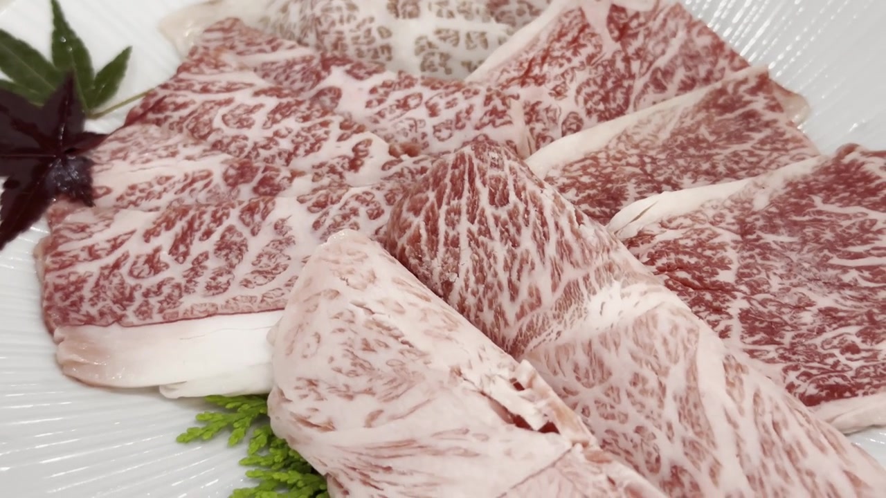 Primer plano de rebanadas de carne de res Wagyu A5 premium dispuestas en un plato de servir, destacando un marmoleado excepcional y una presentación elegante para una cena gourmet.