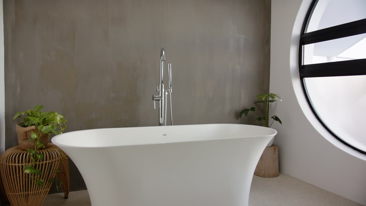 Modern bathroom with white freestanding bathtub and indoor plants for home relaxation, copy space