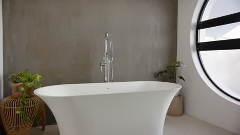 modern bathroom with white freestanding bathtub and indoor plants for home relaxation, copy space