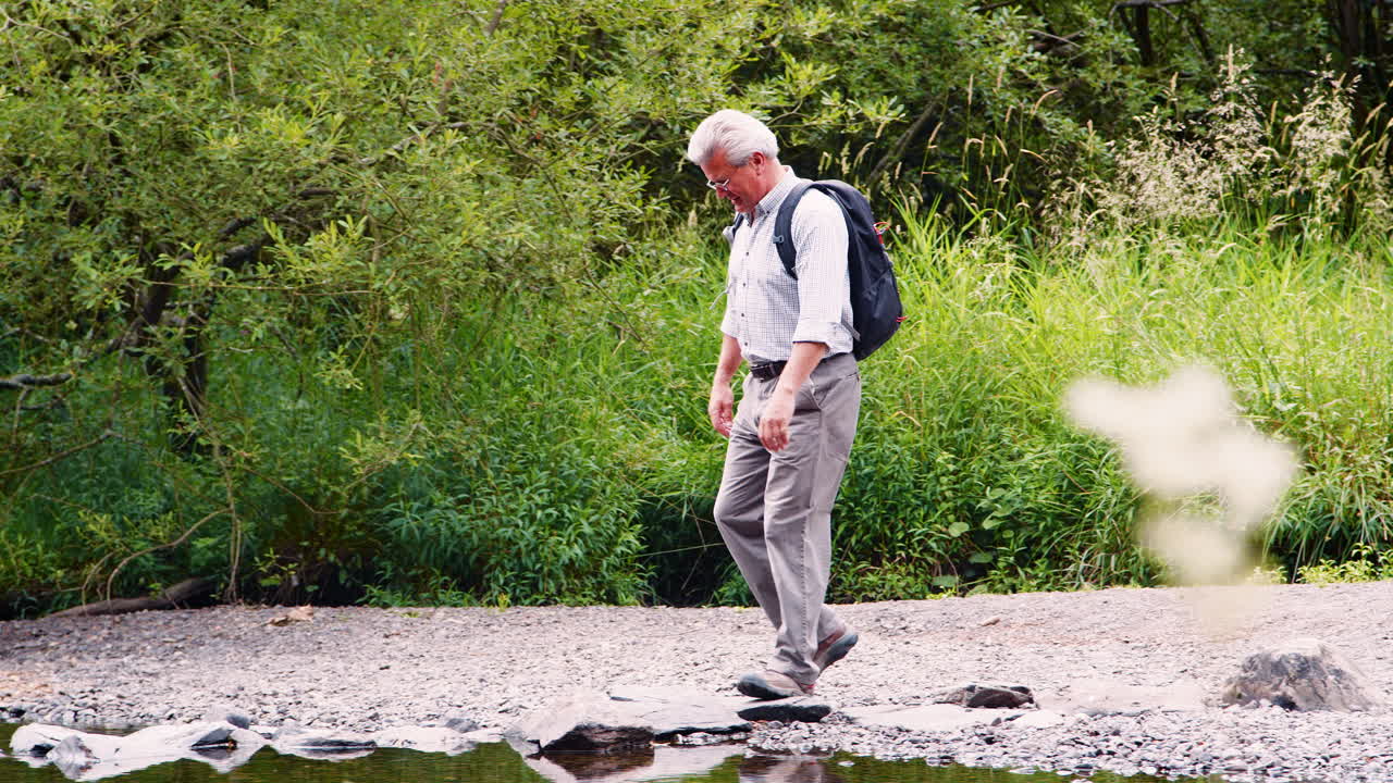 영국 레이크 디스트릭트에서 하이킹하는 동안 강을 건너기 위해 스 ⁇  스톤을 사용하는 고령자의 느린 동작  ⁇