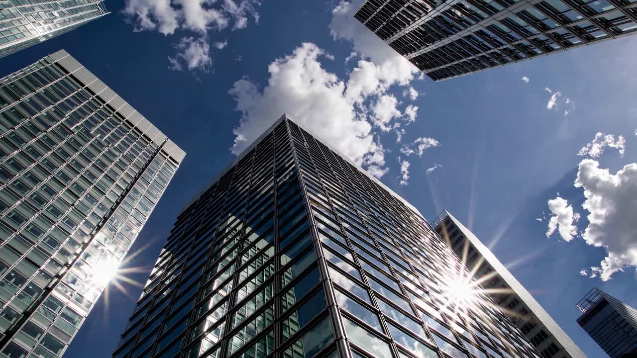 Vídeo dinâmico em ângulo baixo de arranha-céus modernos com céu azul e nuvens