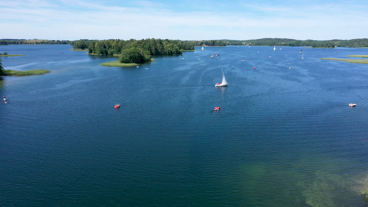 antena: grupo de barcos navegando en la superficie del lago en trakai en un día luminoso y soleado con cielo nublado visible en el fondo