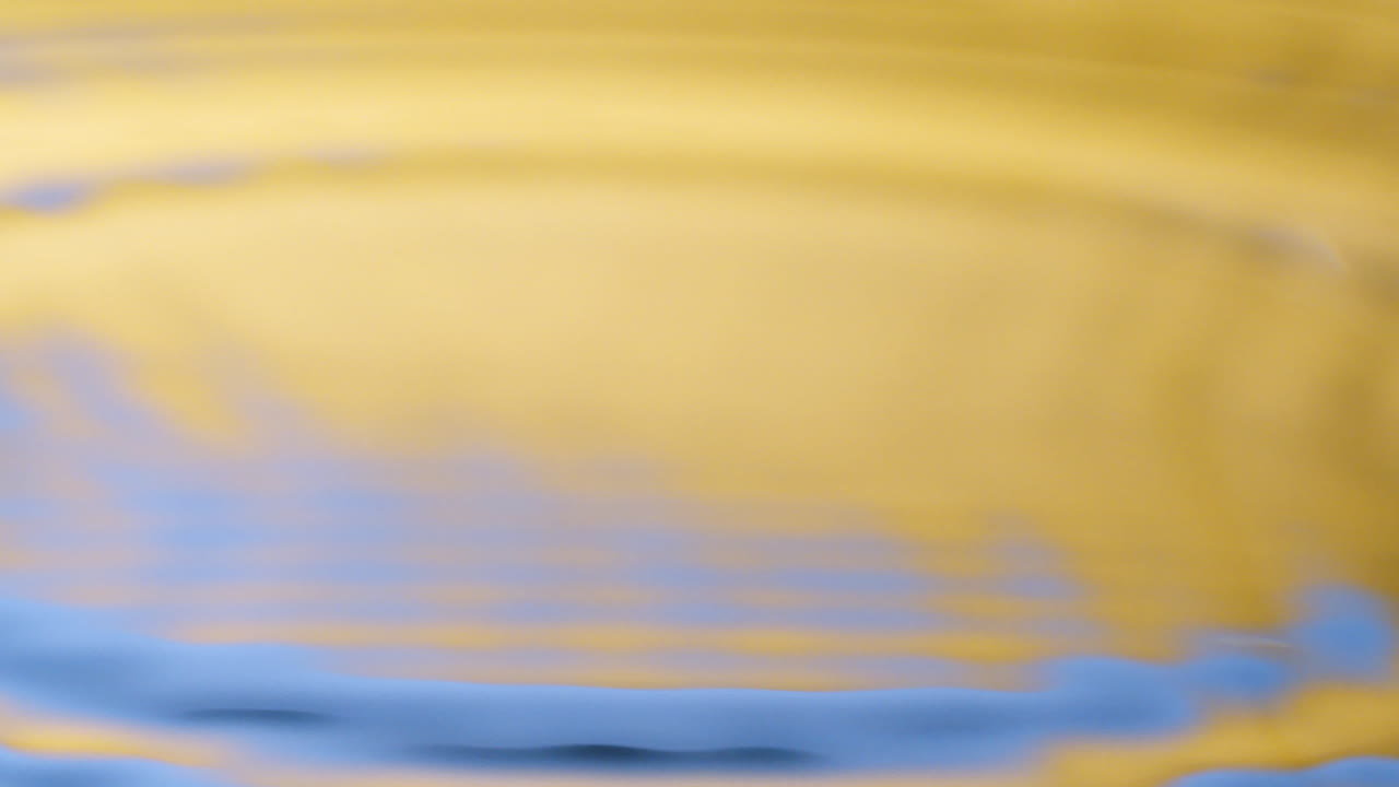 Close up real of water drop falls into water and diverging circles of water with smoot color background in studio with copy space for place a text for advertisement.