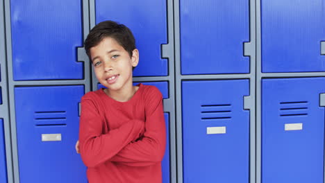 in a school hallway, a young caucasian boy leans against blue lockers