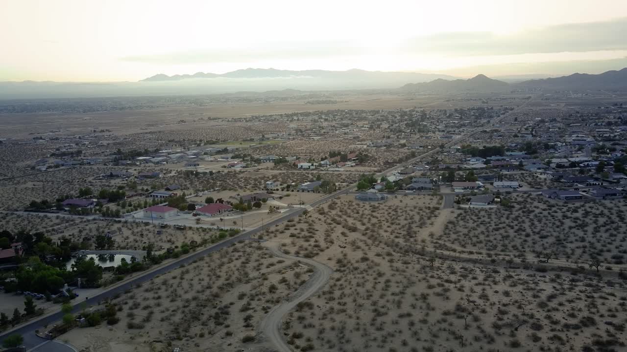 Una veduta aerea panoramica con drone sopra la secca cittadina desertica d'alta quota di Apple Valley durante l'estate in California