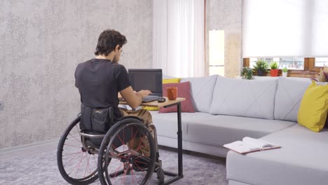 Behinderter-Junger-Mann-Sitzt-Im-Rollstuhl-Und-Arbeitet-Mit-Laptop.