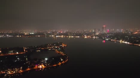 Oscuro-Horizonte-Nocturno-De-La-Ciudad-Y-Lago-Con-Neblina-Atmosférica-En-La-Distancia