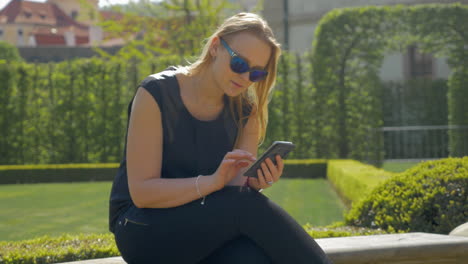 Woman-spending-leisure-time-with-cell-in-green-park