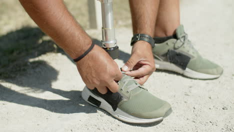 Close-up-of-man-with-bionic-leg-tying-laces-on-athletic-shoes