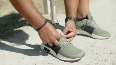 close-up of man with bionic leg tying laces on athletic shoes