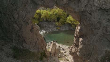 gorgeous drone shot flying through a rock formation towards a beautiful river in argentina