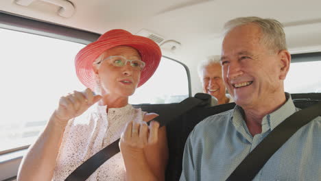 group of senior friends sitting in back of people carrier being driven to vacation