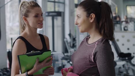 Instructor-De-Fitness-Y-Mujer-Charlando-Antes-De-La-Sesión-De-Gimnasio.