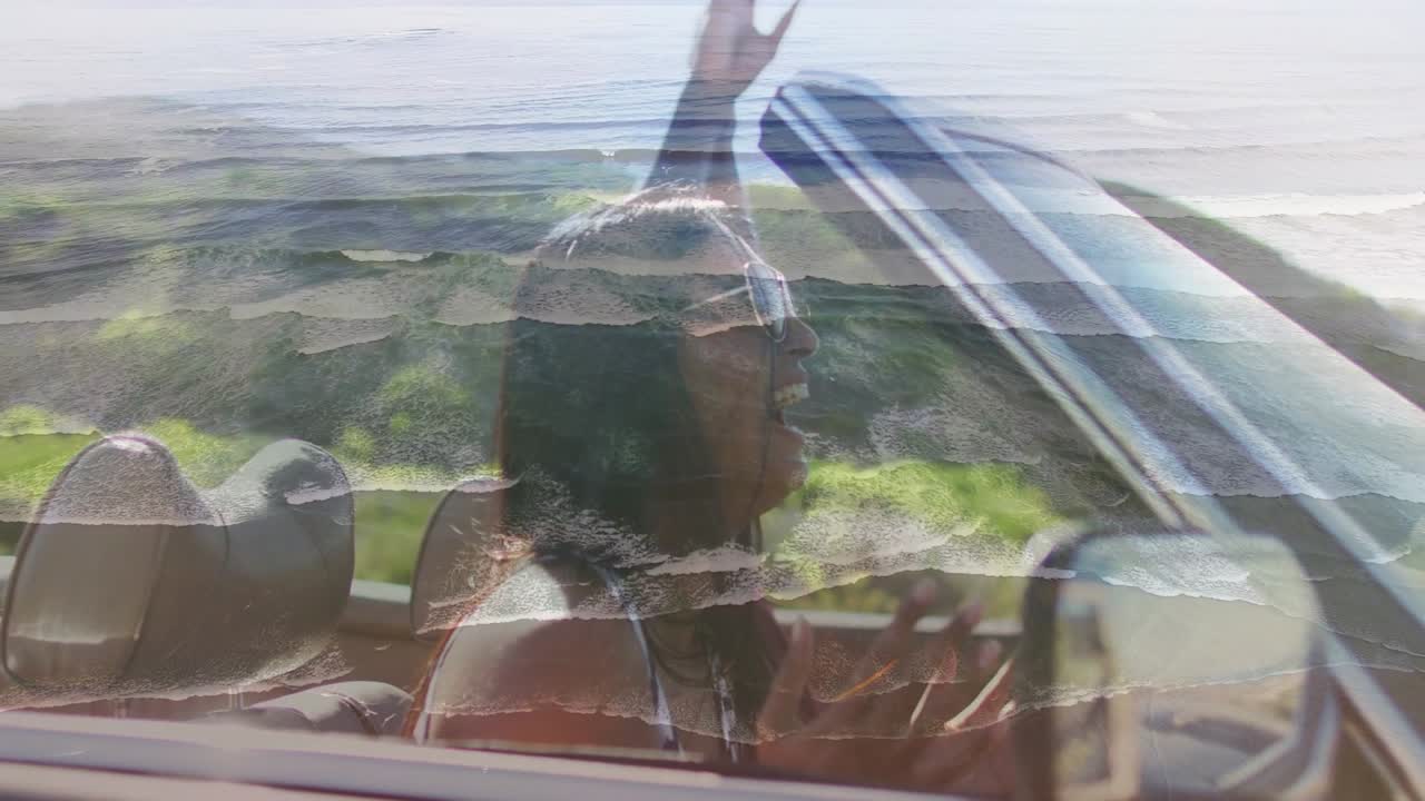 Donna che alza le mani, braccia al cielo piene di energia; conducente alla guida, entrambi sorridono in un'auto da viaggio; sovrapposizione grafica scorrevole.