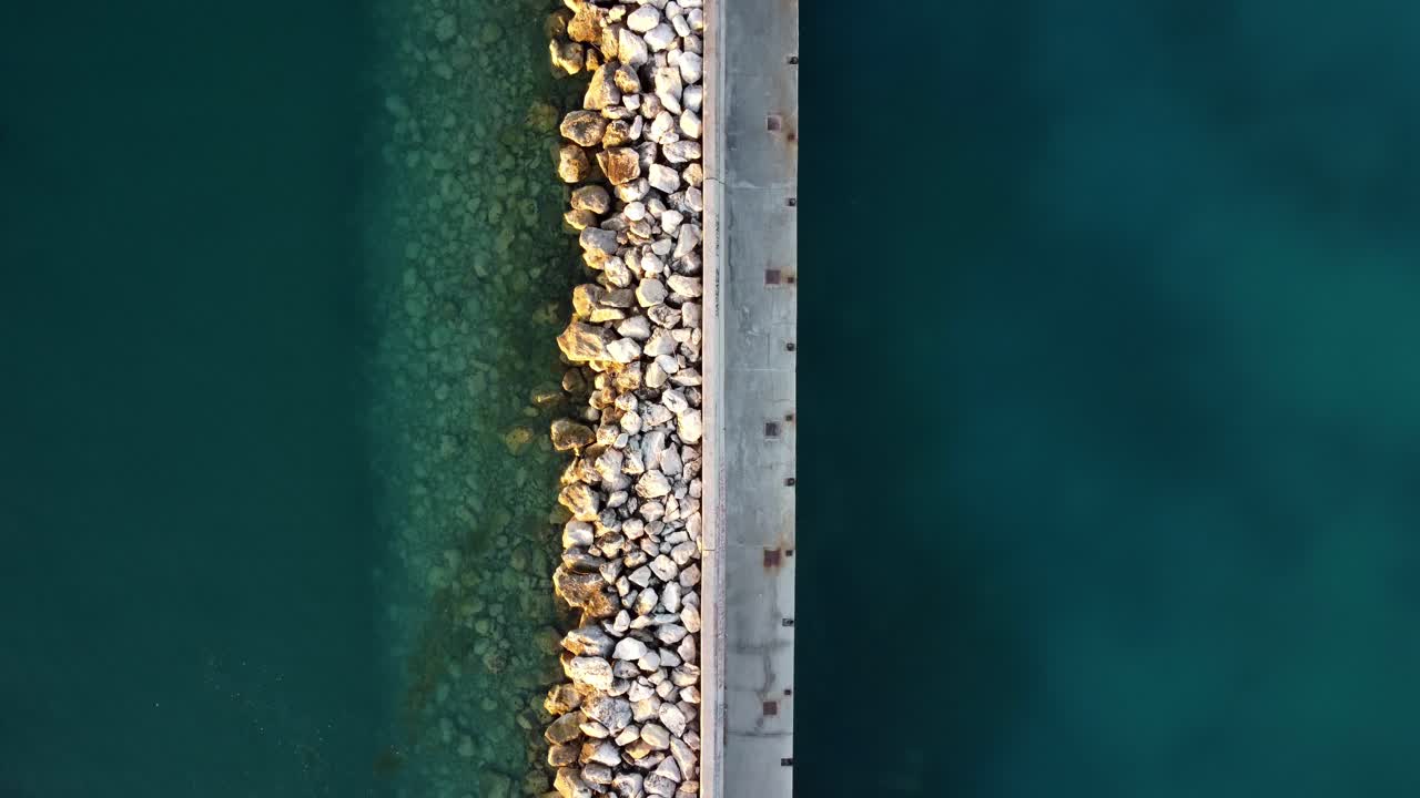 Vista dall'alto di una marina con rocce e acque turchesi.