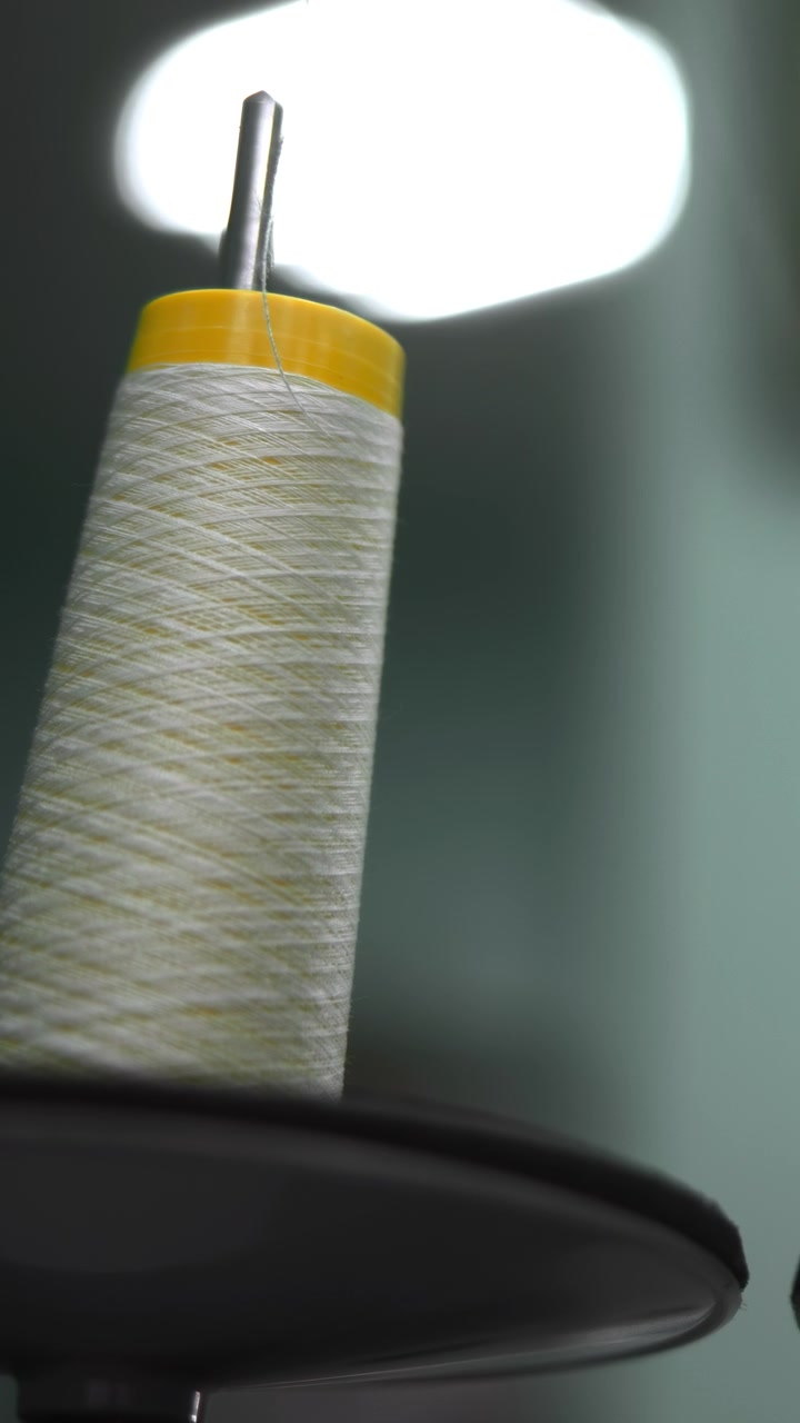 Closeup Spools Of White Thread On Industrial Sewing Machine, Blurred Seamstress In Background, Soft Studio