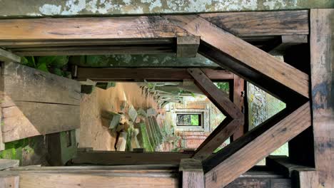 vertical view walking forward pov through a stone gate into the prasat kraham of the koh ker temple ruins, cambodia