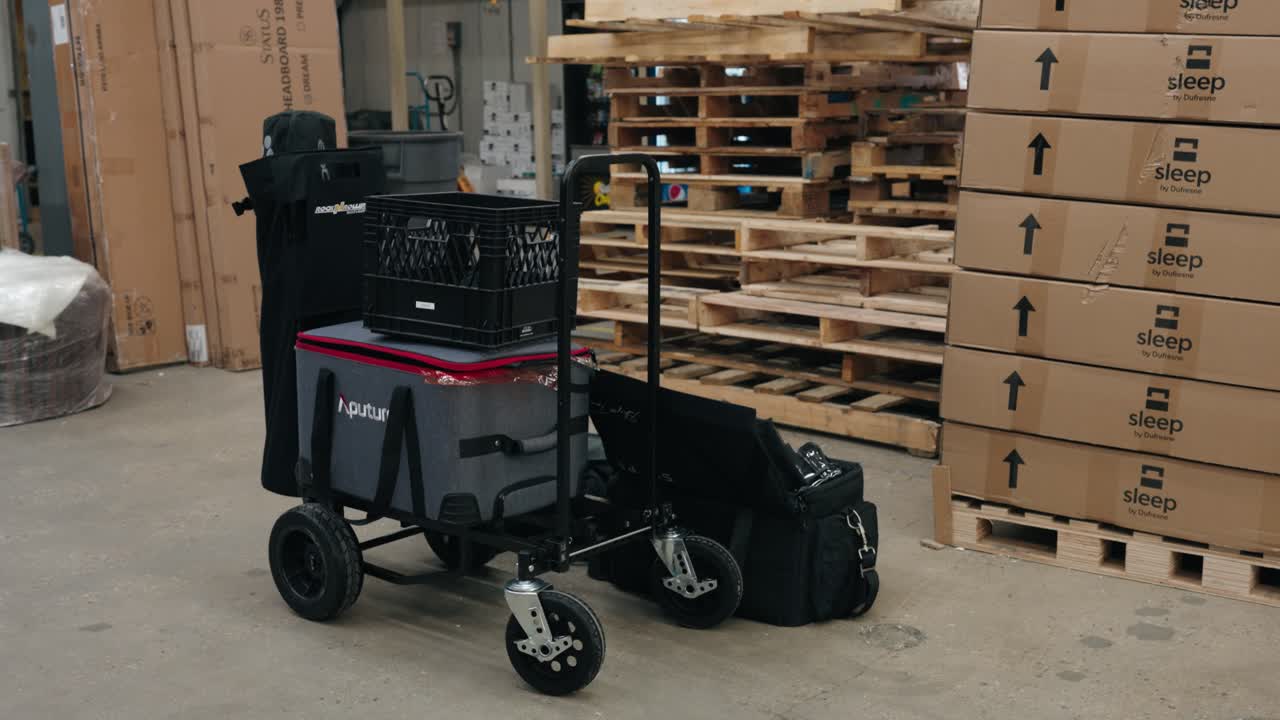 Cart with video production gear in an industrial setting, camera bag on floor