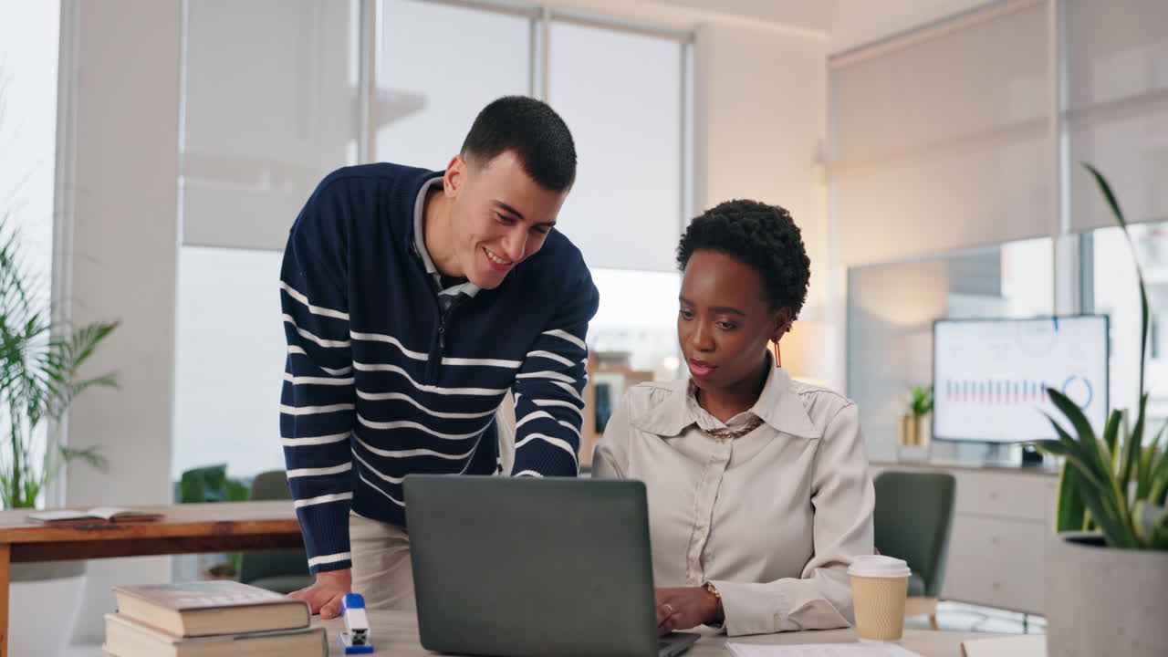 Two colleagues working together on a laptop in an office