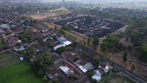 Aerial-view-of-a-group-of-cyclists-passing-the-edge-of-the-Prambanan-temple,-which-is-a-cadi-with-Hindu-religious-patterns