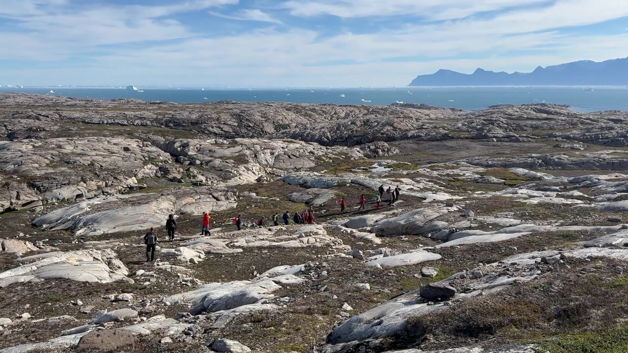 Gruppo di escursionisti scende lungo un pendio roccioso sull'isola di Danimarca, Scoresbysund, Groenlandia
