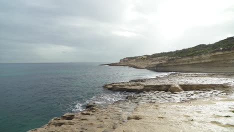 shallow water washes the shore of stone beach il-kalanka in malta
