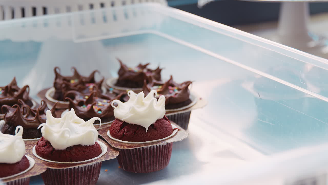 Panettiere che posiziona un muffin glassato su un vassoio di muffin in una pasticceria