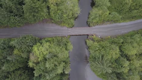 Aerial-view-of-one-lane-bridge-over-a-small-lazy-river