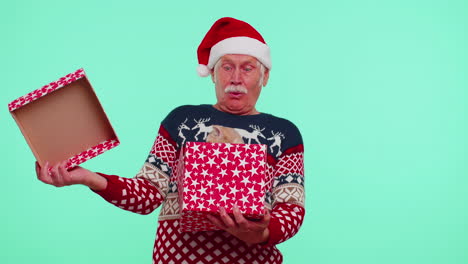 grandfather in christmas sweater smiling, unwrapping gift, opening box with pet cat, great surprise