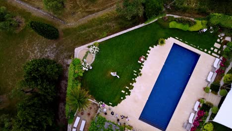a topdown spining drone view of a couple of married people dancing in a garden by the pool