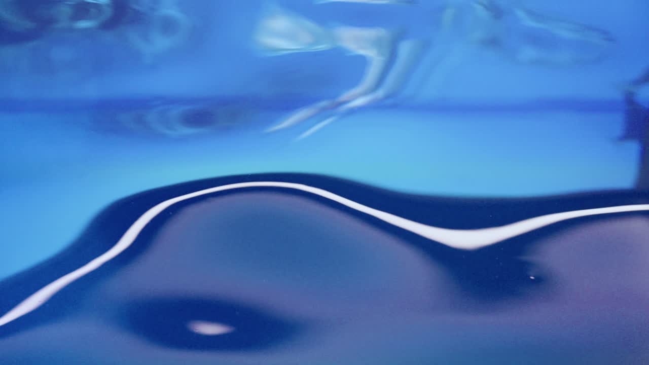 A smooth, vibrant blue water surface with light ripples and reflections—capturing a calm, clear moment, possibly in a pool or artificial basin