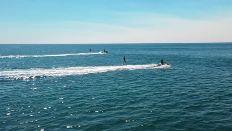 jet ski towing athletes hydro foiling on the ocean on blue summer's day in sydney, nsw, australia. water sports aerial.